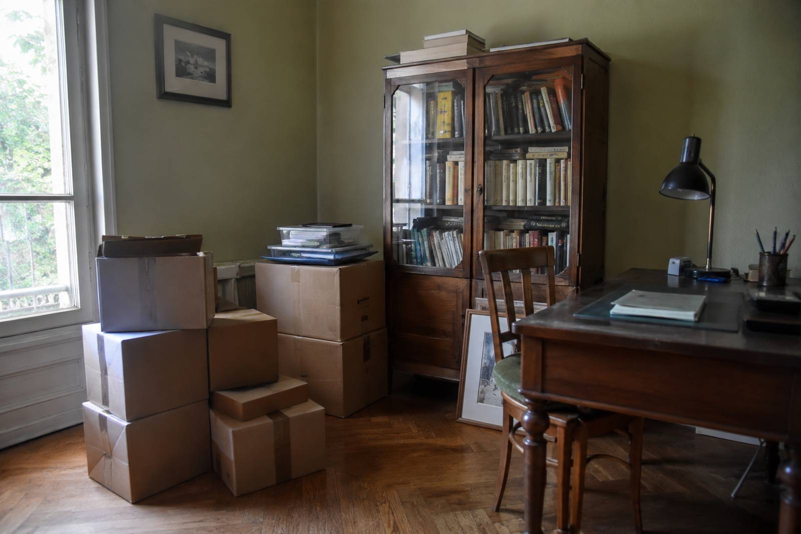 Bureau avec bibliothèque et cartons de rangement dans une pièce peu utilisée.