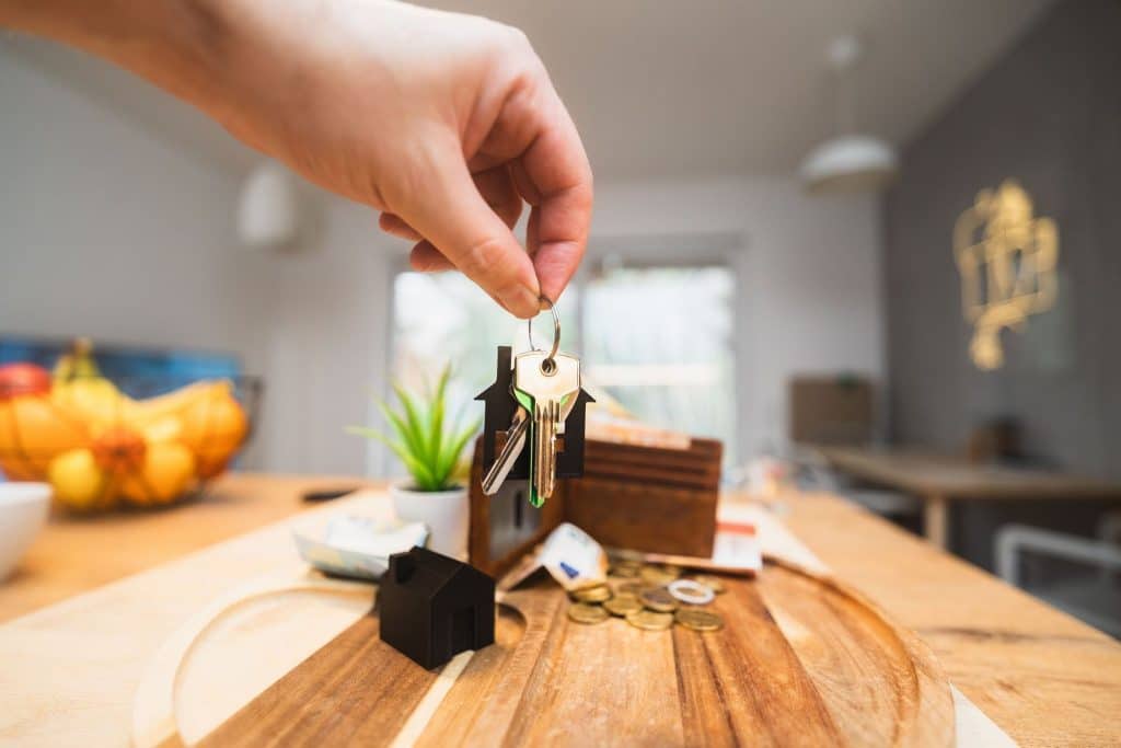Main tenant un trousseau de clés au-dessus d'une table, illustrant les objets du quotidien qui s'accumulent dans le logement.